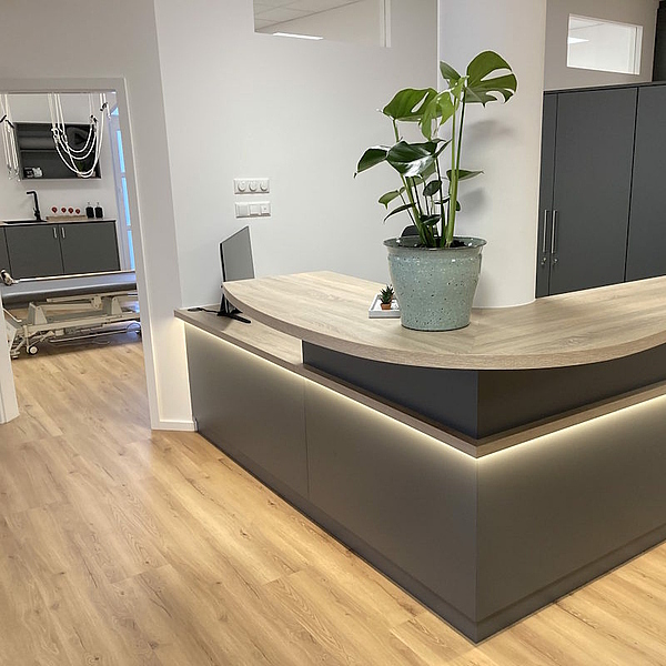 Moderne Empfangstheke aus Schichtstoff in Anthrazit mit abgerundetem Thekenbrett – maßgefertigte Praxismöbel und Ladenbau von Hofmann, auch für Gastro Möbel geeignet.